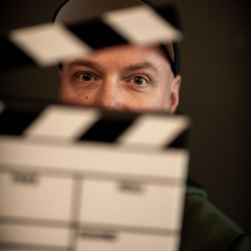 Mitarbeiter von Rittler & Co hält eine Filmklappe vor sein Gesicht