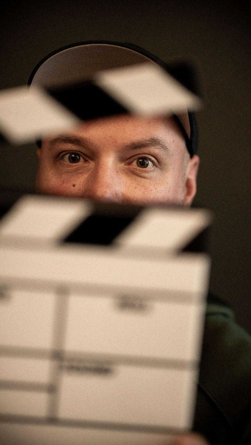 Mitarbeiter von Rittler & Co hält eine Filmklappe vor sein Gesicht