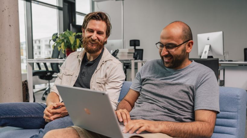 Thomas und John lachen in einen Laptop