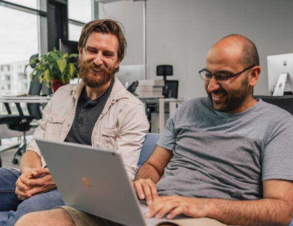 Thomas und John lachen in einen Laptop