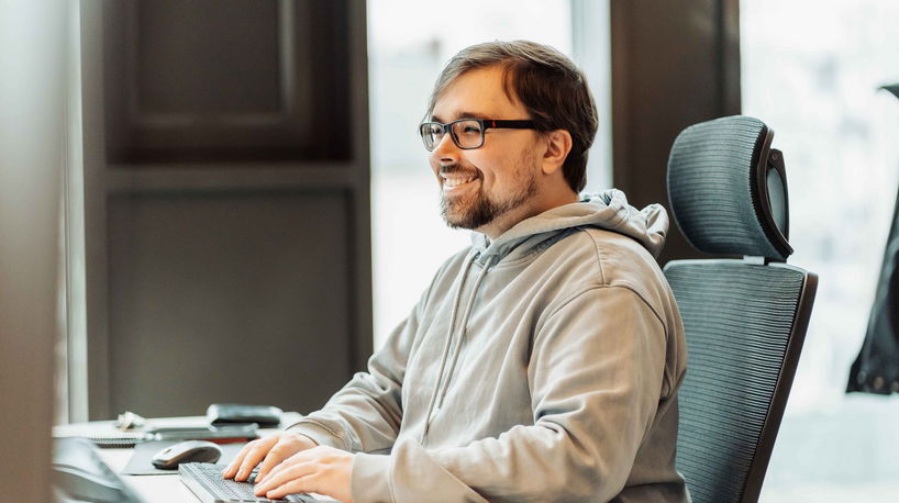 Ein Porträt eines lächelnden Mannes, der sichtlich Freude am Programmieren hat.