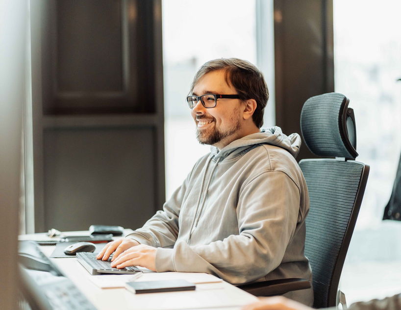 Ein Porträt eines lächelnden Mannes, der sichtlich Freude am Programmieren hat.