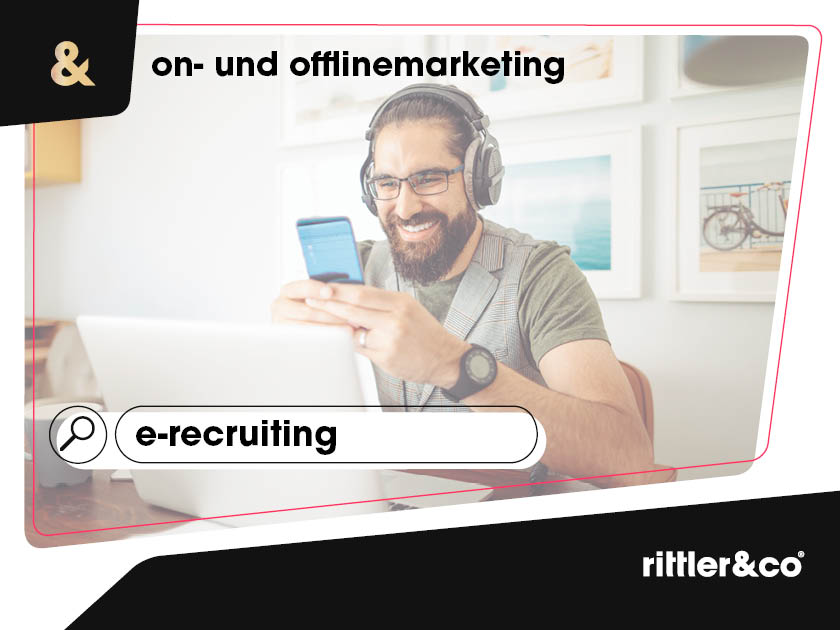 Mann arbeitet an seinem Laptop, schaut auf das Telefon und lächelt 02